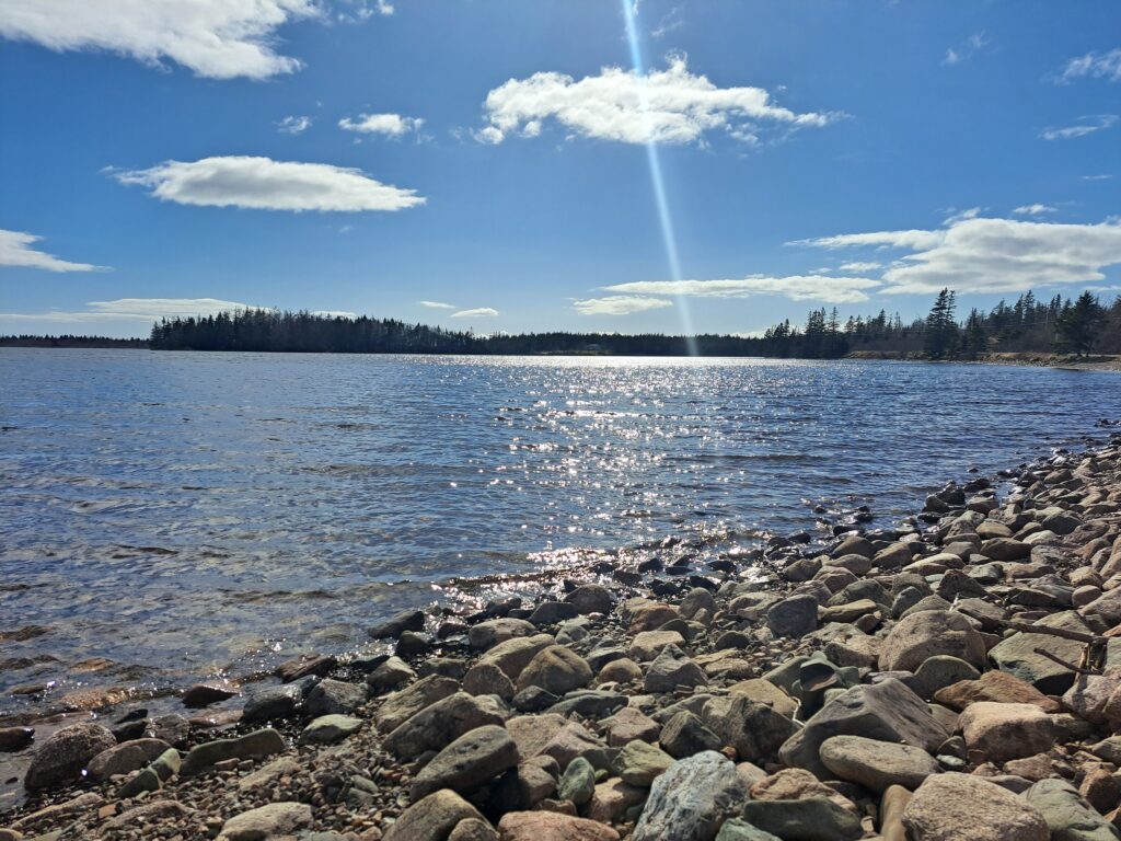 Seeaussicht von einem Steinufer bei Sonnenschein